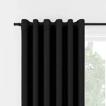 Black eyelet curtains hanging on a black rod.