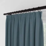 Close-up of pleated blue curtains with black hanging rings