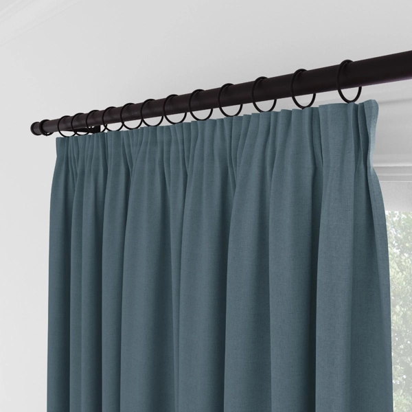 Close-up of pleated blue curtains with black hanging rings