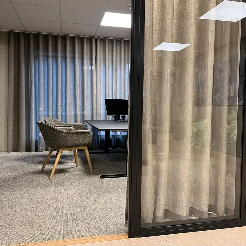 Office workspace seen through a glass door and curtain.